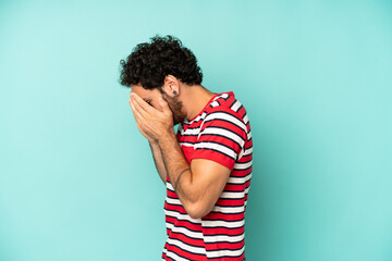 young bearded man covering eyes with hands with a sad, frustrated look of despair, crying, side view