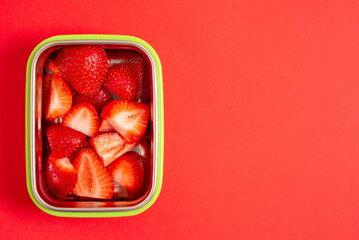 Strawberries in a snack container on a red background