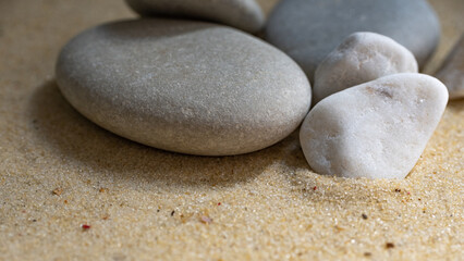 small gray pebbles on a sandy beach, close shot