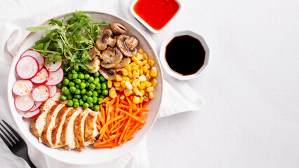 Chicken buddha bowl with meat, colorful vegetables on base of brown rice.