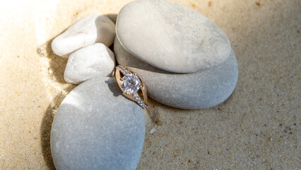 Fototapeta na wymiar gold ring with a large diamond in stones on golden sand