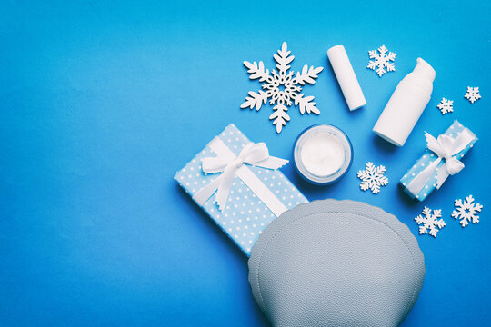 Christmas flat lay with makeup cosmetic products in cosmetic bag on colored background. Top view New year Beauty concept