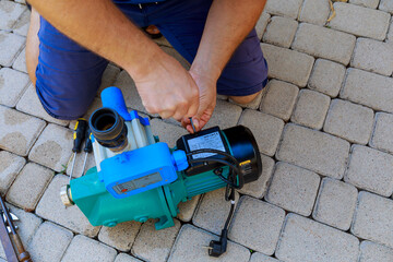 The plumber repairs the water pump, unscrews the cover to the electronics with a screwdriver. Repair of equipment.