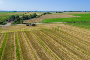 Top view of a tractor moving across a field with a trailer near a field road. Agricultural machinery on the farmer's field.