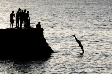 meninos mergulhando do dique na praia do porto em salvador