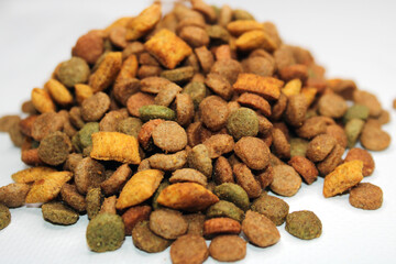 Dry food for cats, dogs lies in a pile on a light background. Close-up. Blurred background and background
