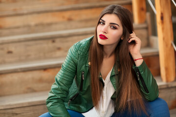 Fashion outdoor portrait of gorgeous long hair woman in green leather jacket and red lips, autumn...
