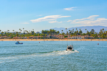 Obraz premium Santa Barbara Harbor. Boats on water, silhouette of city, palm trees, mountains, and cloudy sky on background