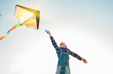 9YO Girl with flying colorful kite running on the high grass meadow in the mountain fields. Low...