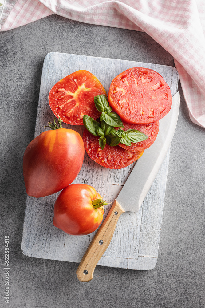 Sticker sliced bull heart tomatoes on cutting board.