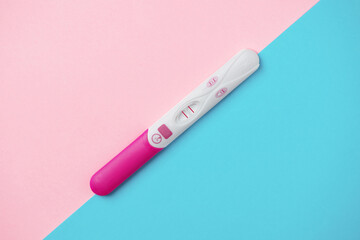 Positive pregnancy test on pink and blue background. Positive result of pregnancy test. Guessing unborn baby gender.