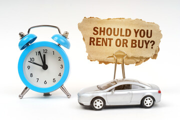 On a white surface there is a blue alarm clock, a car and a sign with the inscription - Should you rent or buy