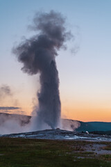 Old Faithful geyser erupts in Yellowstone National Park at sunset