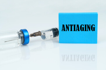 On a white reflective surface there is a syringe with an ampoule and a plate with the inscription -...