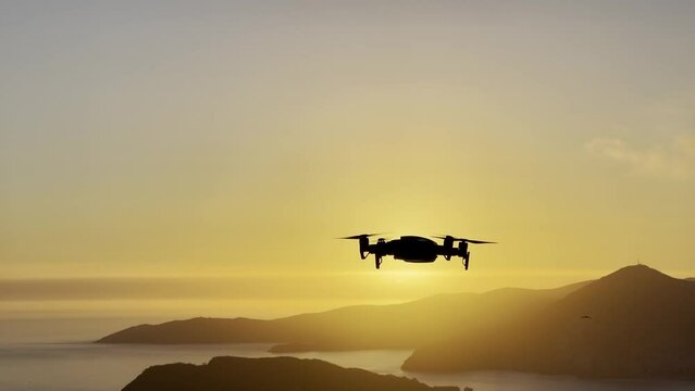 Drone flies over the sea against the backdrop of the setting sun