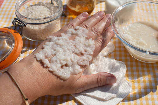 Rice grains on hand. Woman testing rice mask, natural homemade beauty product.