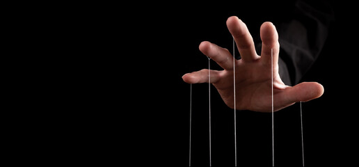 Hand closeup pulling strings, manipulating, controlling. Authority concept. Banner with copy space...
