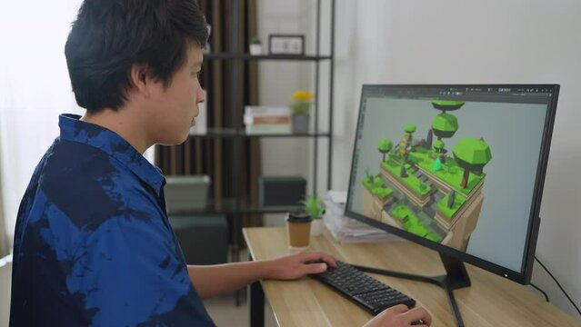 Asian male developer using computer to designer game at home. He designs 3d game and develop game system alone. Technology, Development, Designer, Engineering Concept.