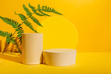 Natural minimal cosmetic background for product presentation. Empty cosmetics podiums on yellow background with shadow and leaves for beauty product.