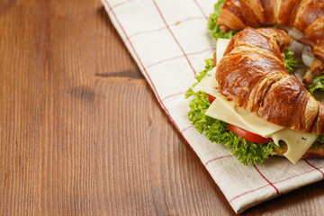 two lye croissant sandwiches with iberian ham, tomato slices, lettuce and cheese on marble board on...