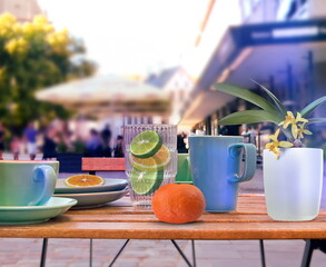 street cafe glass of lemon orange water ,cup of coffee and flowers on wooden table in Tallinn old...