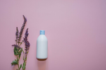 White plastic bottle with lavender flowers on a violet background. Copy space. Top view