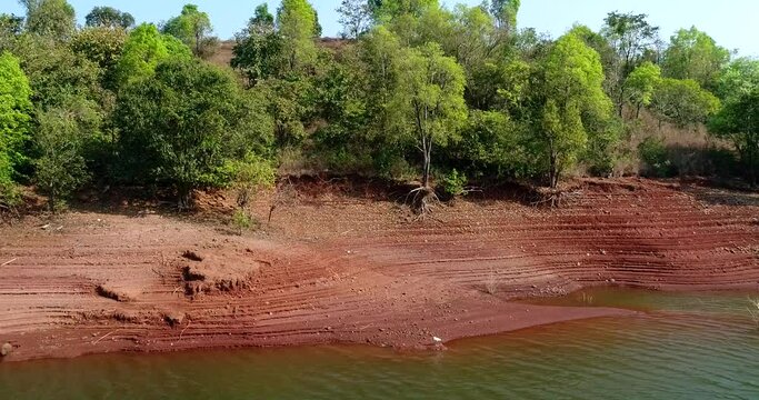 Aerial shot of white bird on river bank with reddish soil, stairs shape