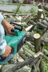 Obraz premium A male uses a chainsaw to cut up a log into firewood.