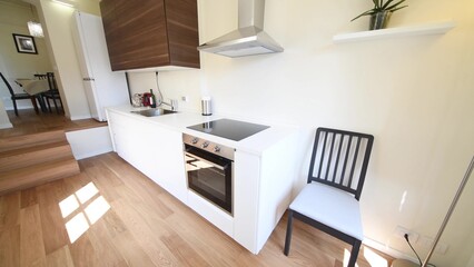 Modern kitchen with white furniture and wooden floor, parquet