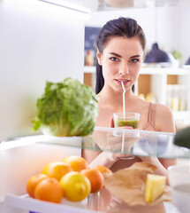 Young woman with glass of tasty healthy smoothie at table in kitchen