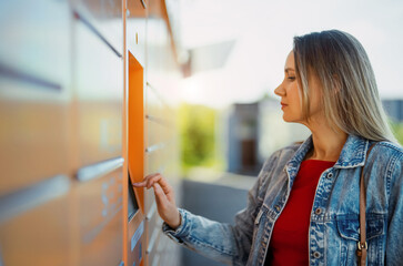 Woman picks up mail from automated self-service post terminal machine.