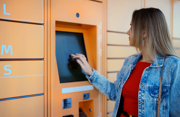 Woman picks up mail from automated self-service post terminal machine.