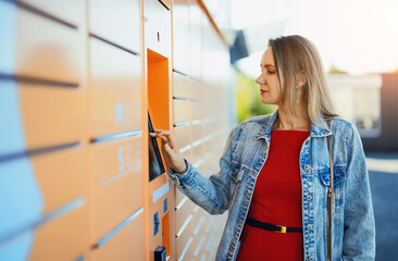 Woman picks up mail from automated self-service post terminal machine.
