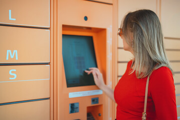 Woman picks up mail from automated self-service post terminal machine.