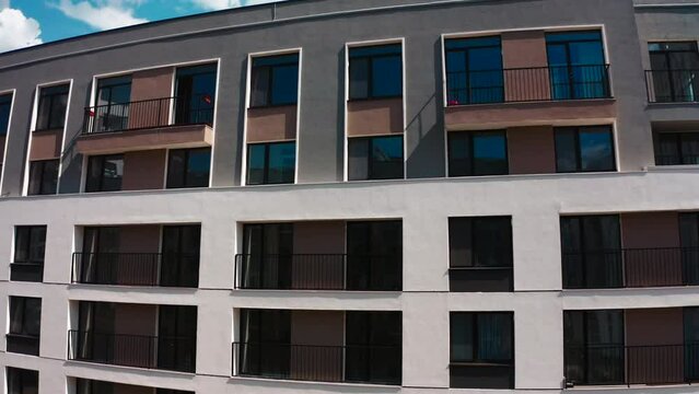 Apartment blocks with balconies. Stock footage. Aerial view of an apartment building on a blue cloudy sky background.