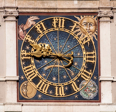 Antique clock with golden hands, numbers, moon and sun on the facade of a Renaissance building in Munich