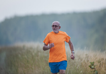Fototapeta premium Senior man running in forest in summer time