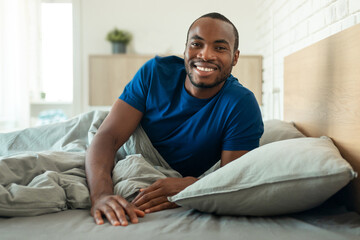 Happy African American Man Smiling Lying In Bed At Home