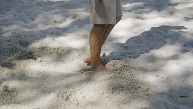 A man levels the sand with his foot on a sandy platform. Close-up shooting