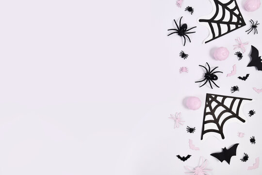Pink and black Halloween decoration on side of white background with copy space