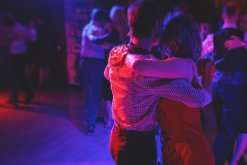 Couples dancing traditional latin argentinian dance milonga in the ballroom, tango salsa bachata kizomba lesson in the red and purple lights, dance festival - obrazy, fototapety, plakaty