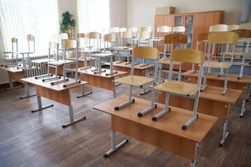 Empty school classroom during cleaning and disinfection. Preparation for the beginning of the school year and school lessons. The chairs are on the desks. Selective focus.