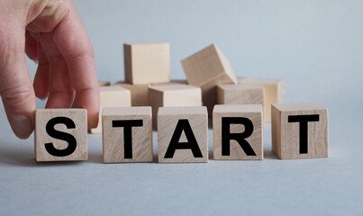 START inscription on the texture of wooden cubes. A business man holds a cube in his hand. An inscription on a financial, business or economic theme.