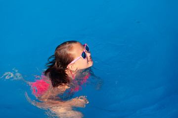 cute girl playing in outdoor swimming pool. Summertime Water Fun.