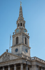 London, UK- July 4, 2022: Trafalgar Square. Spire,, clock Tower and pediment of St. Martin-in-the-fields church against blue sky.