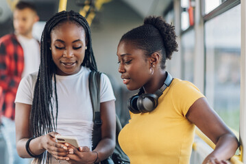Multiracial young female friends talking while riding a bus in the city