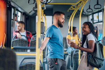 Obraz na płótnie Canvas Multiracial friends talking while riding a bus in the city