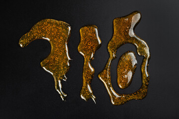 710 lettering golden cannabis wax resin on dark background.