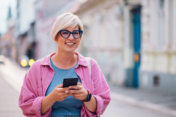 Plus size woman with pixie hair using smartphone in the city street.