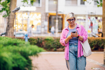 Young plus size woman using smartphone while walking in the city.